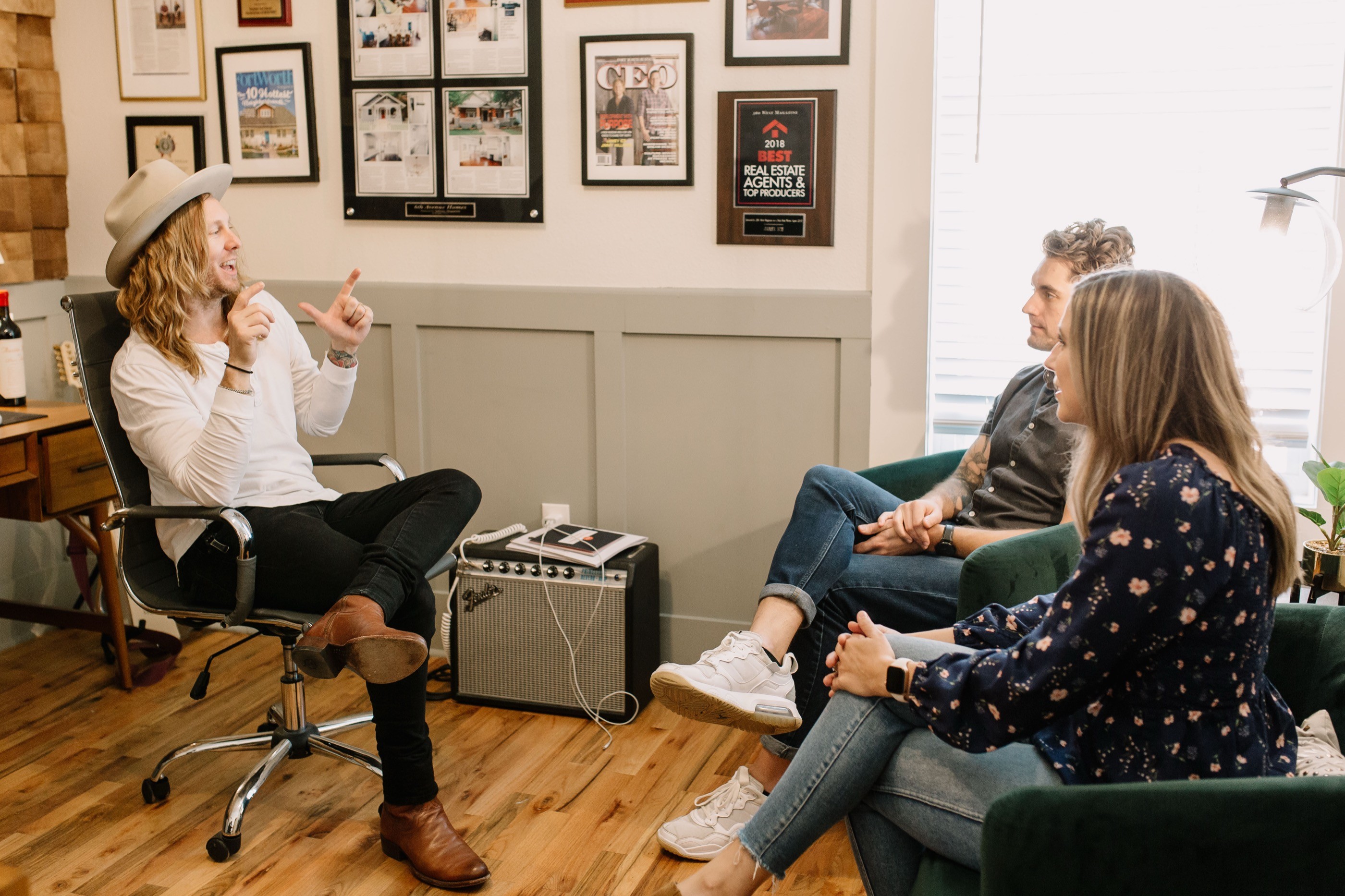 Jamey Ice in his office, talking an idea through with two people on a green sofa.