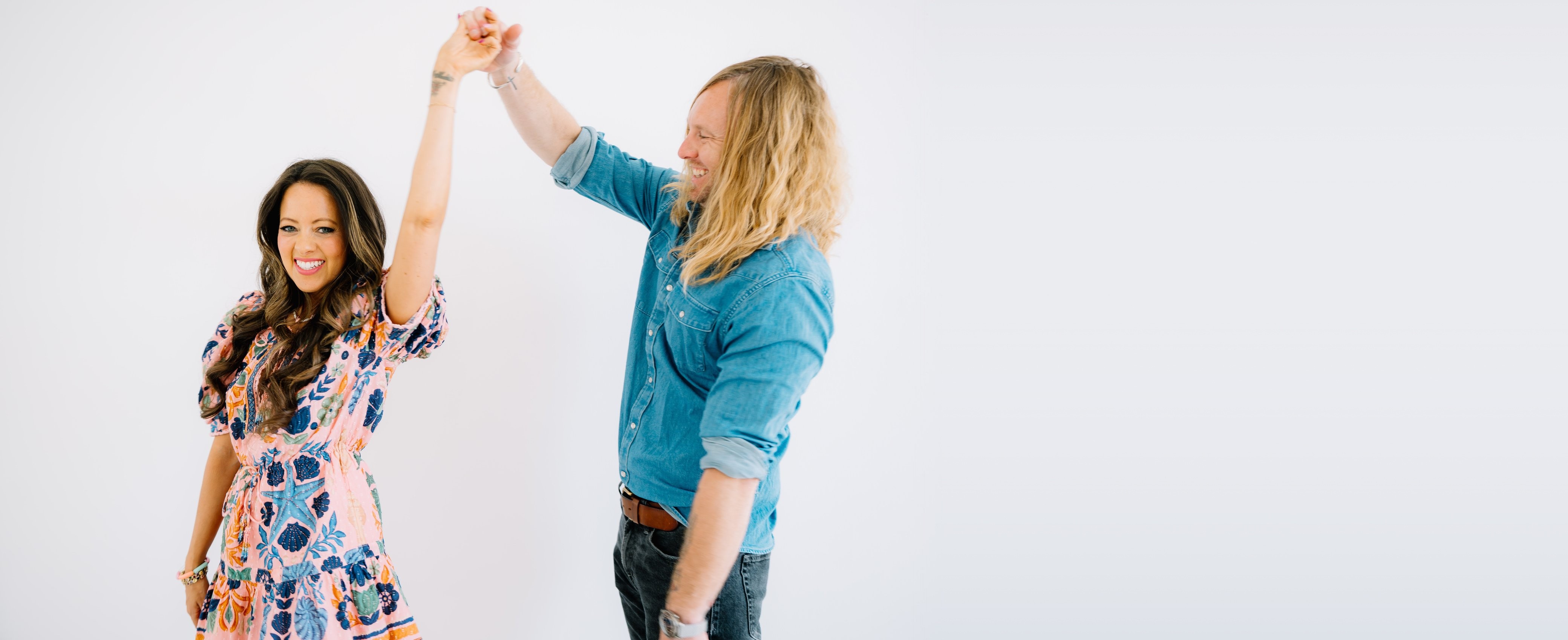 Jamey Ice twirling Melissa under his arm against a white wall