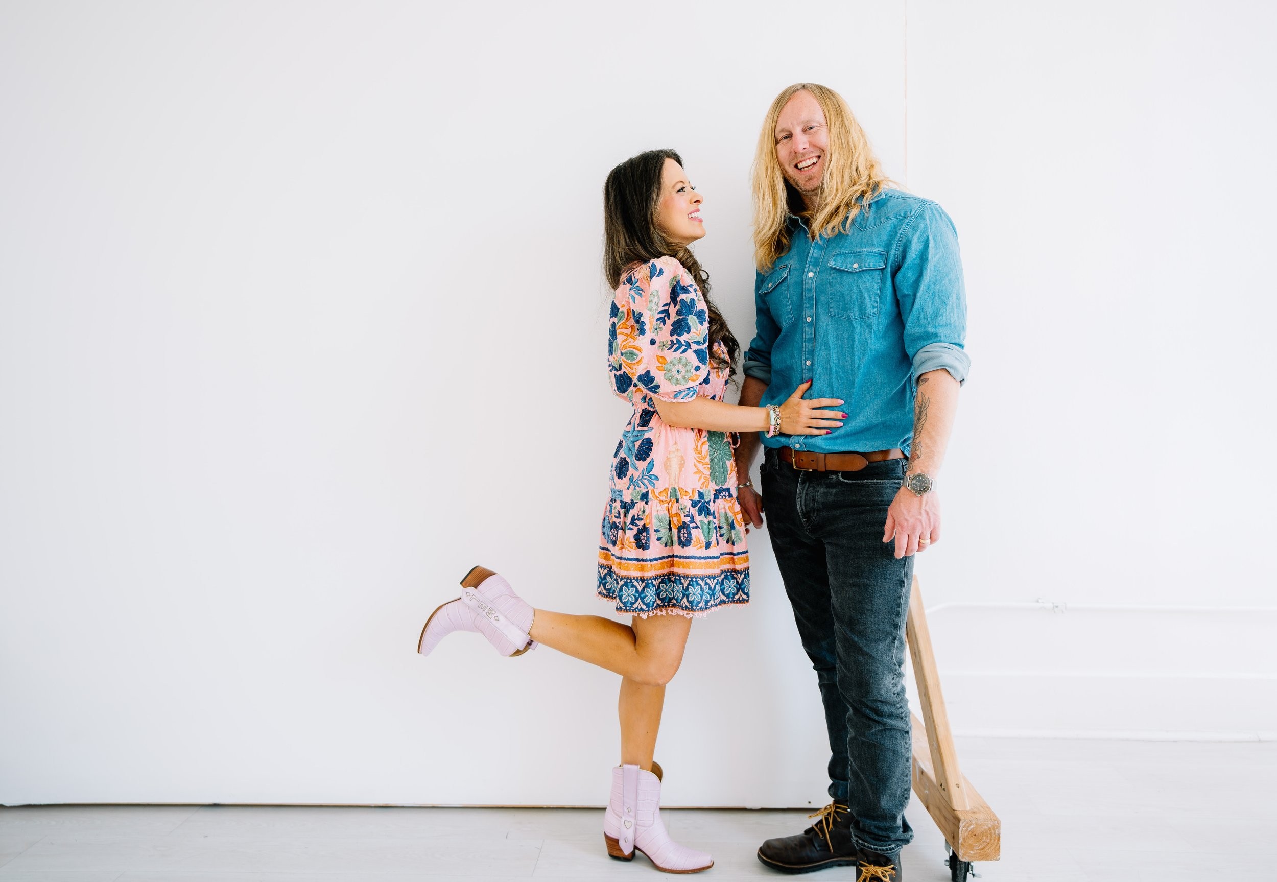 Jamey and Melissa Ice leaning against a white wall, laughing