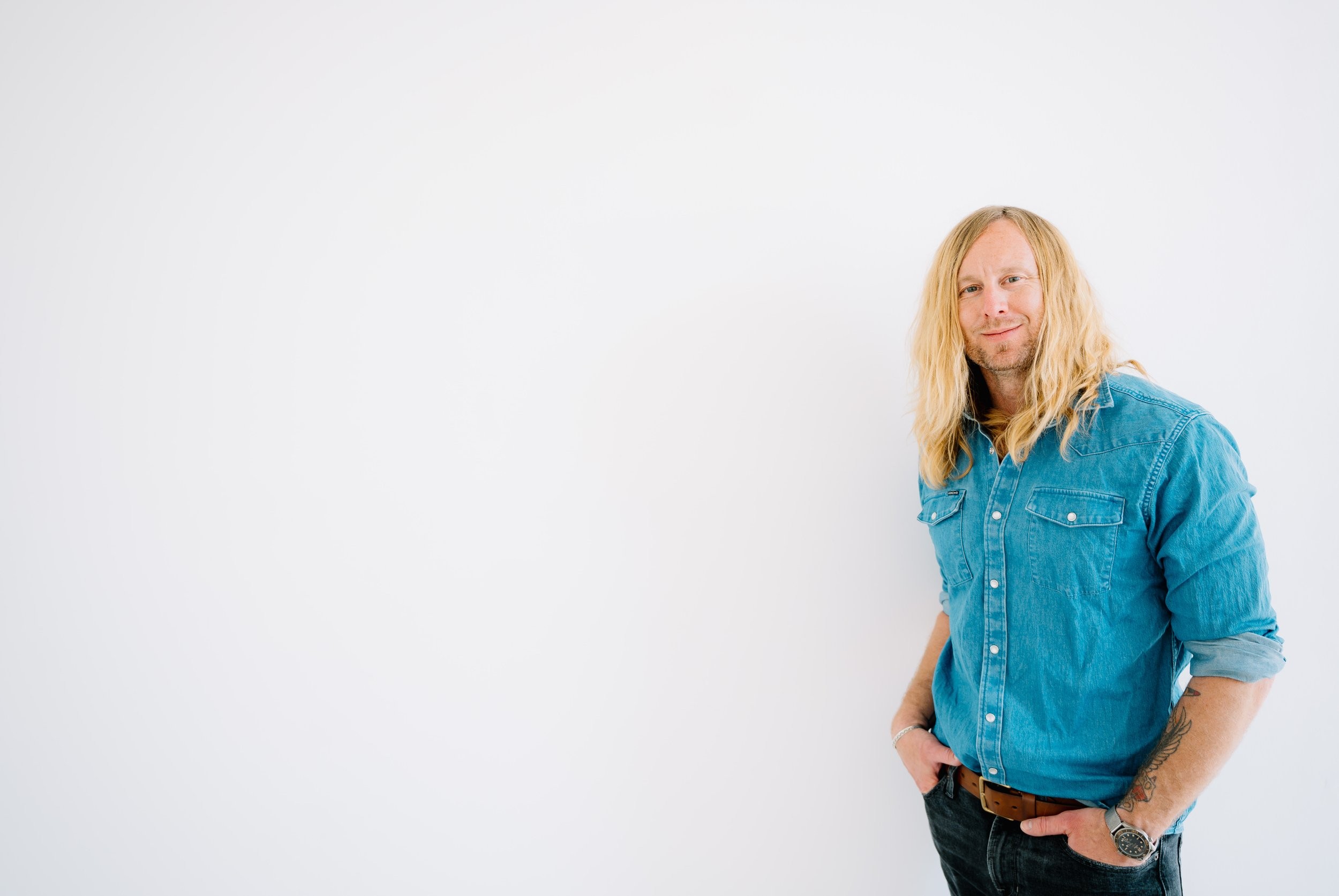 Jamey Ice standing against a white wall, hands in his pockets