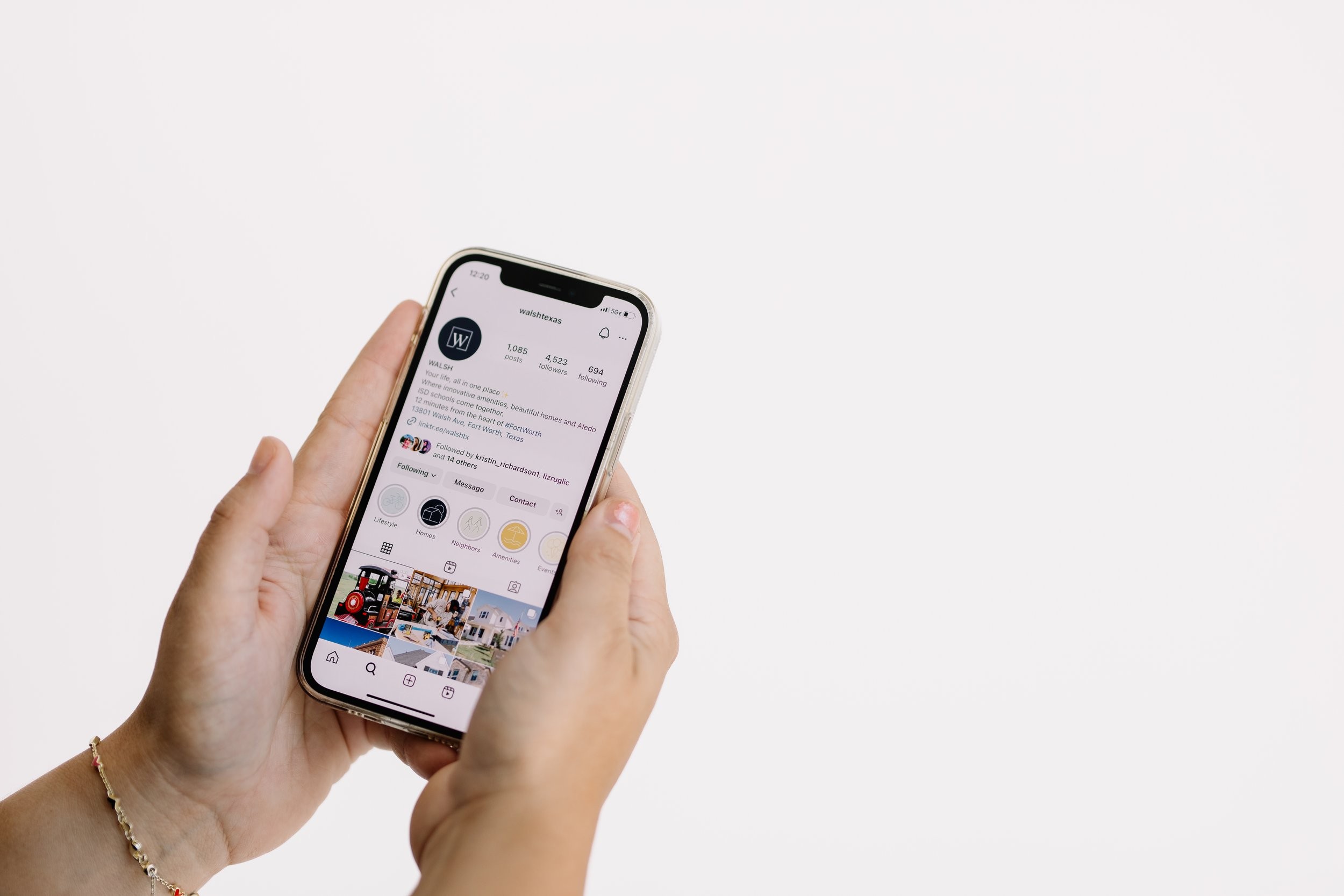 Two hands holding a phone open to a business's Instagram profile.