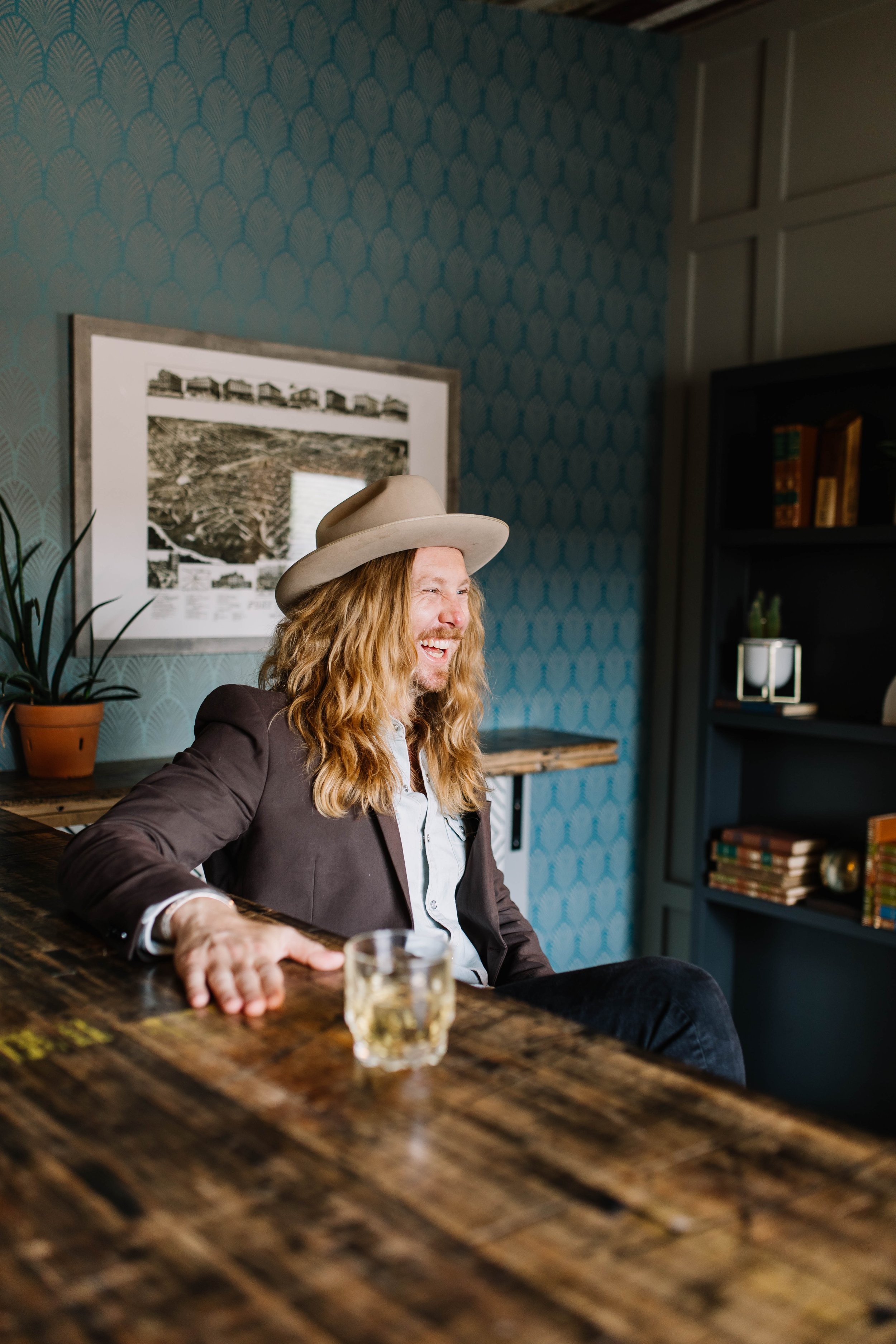 Jamey Ice seated at a wooden table, laughing mid-conversation.