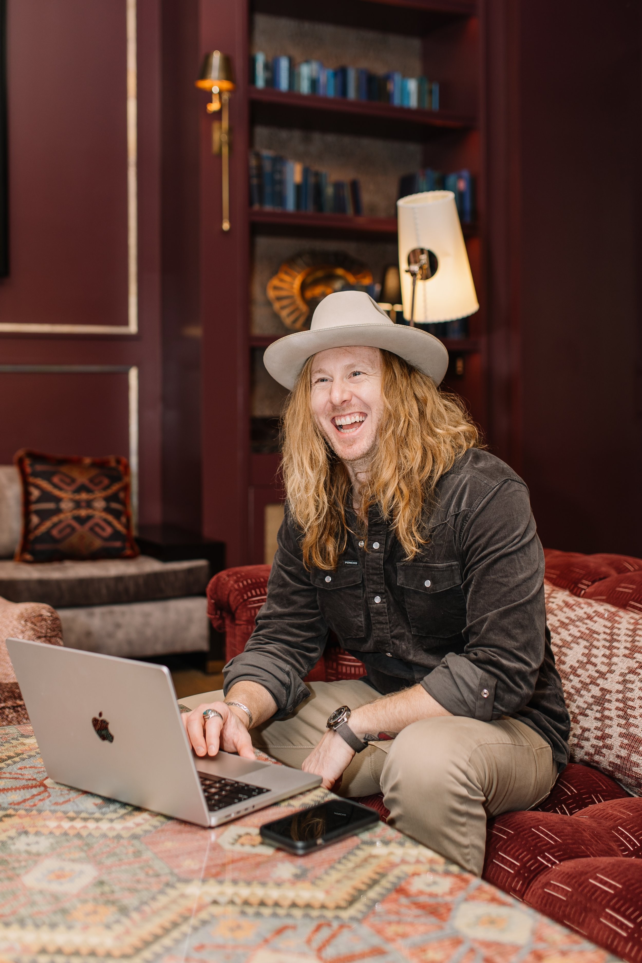 Jamey Ice laughing, working at a laptop in a library room.