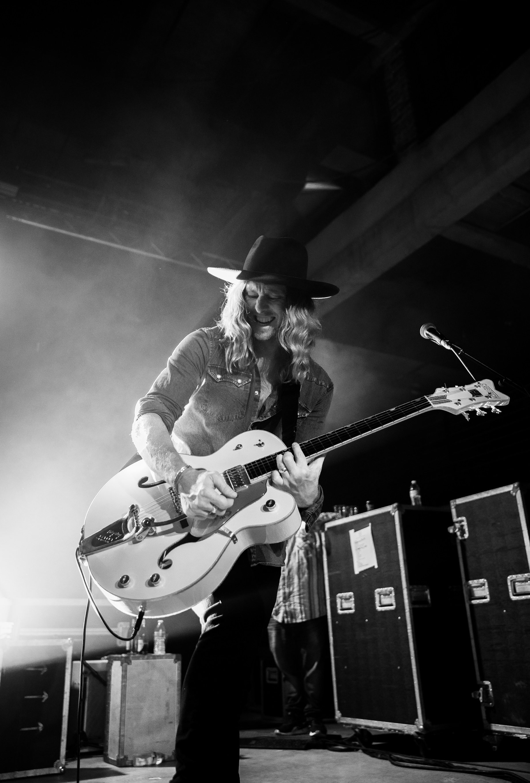 Jamey Ice on stage with a guitar, in black and white.