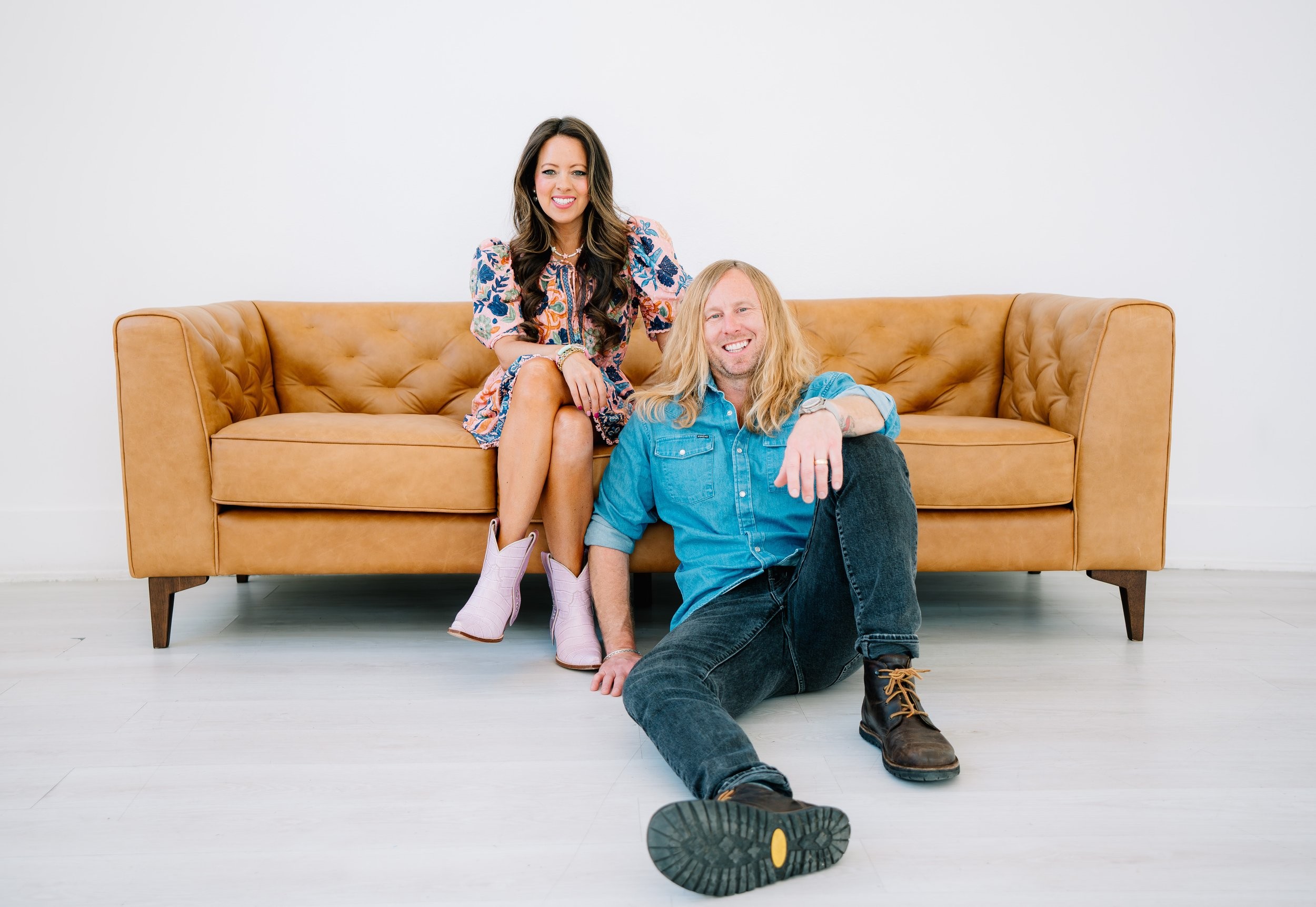 Melissa Ice on a leather sofa with Jamey sitting on the floor beside her