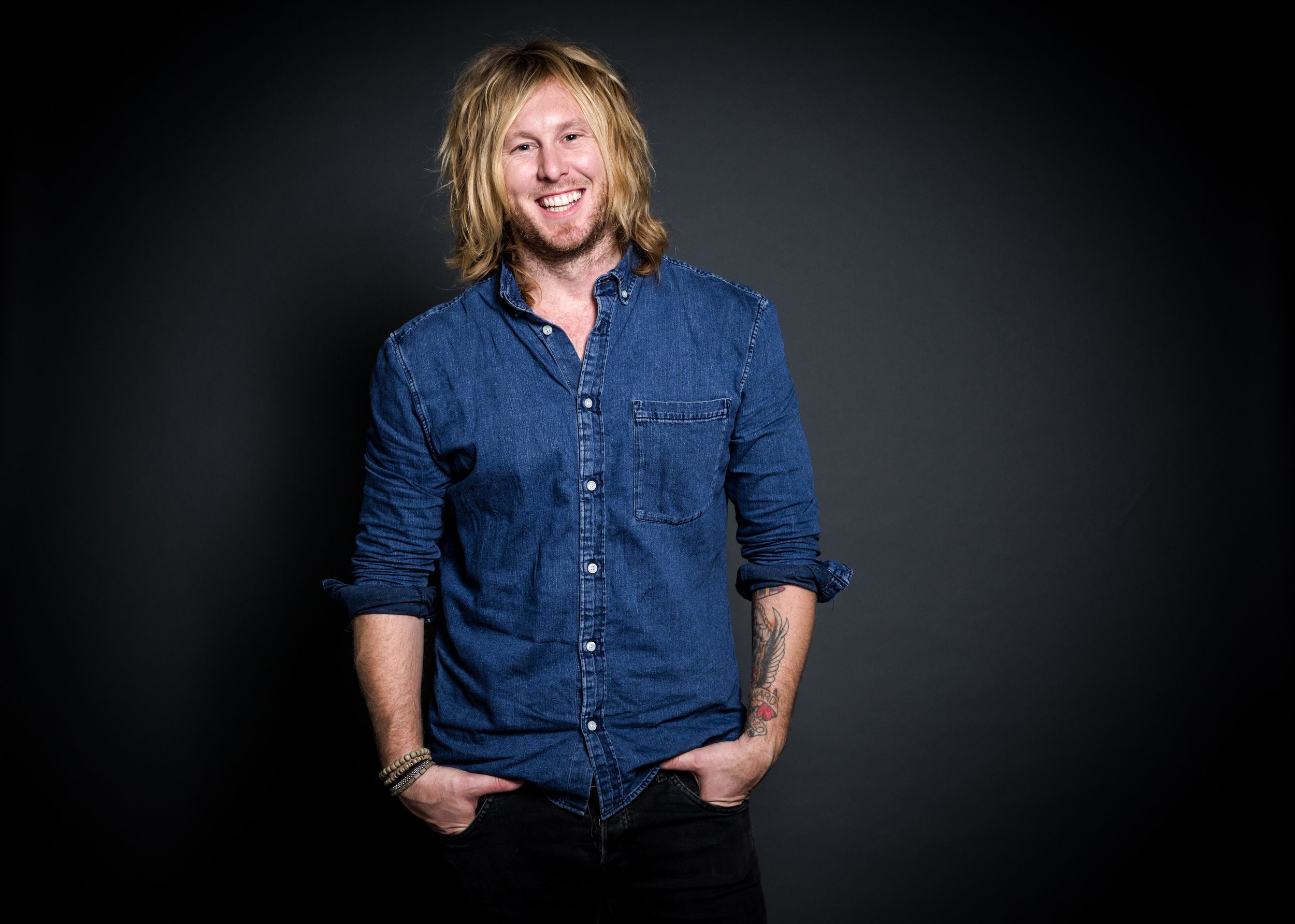 Jamey Ice in a denim shirt against a dark studio wall.